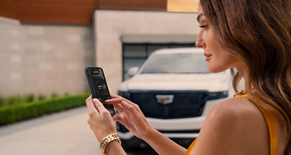 lady checking her mobile with a Cadillac vehicle background | Ed Morse Cadillac Brandon FL in Brandon FL